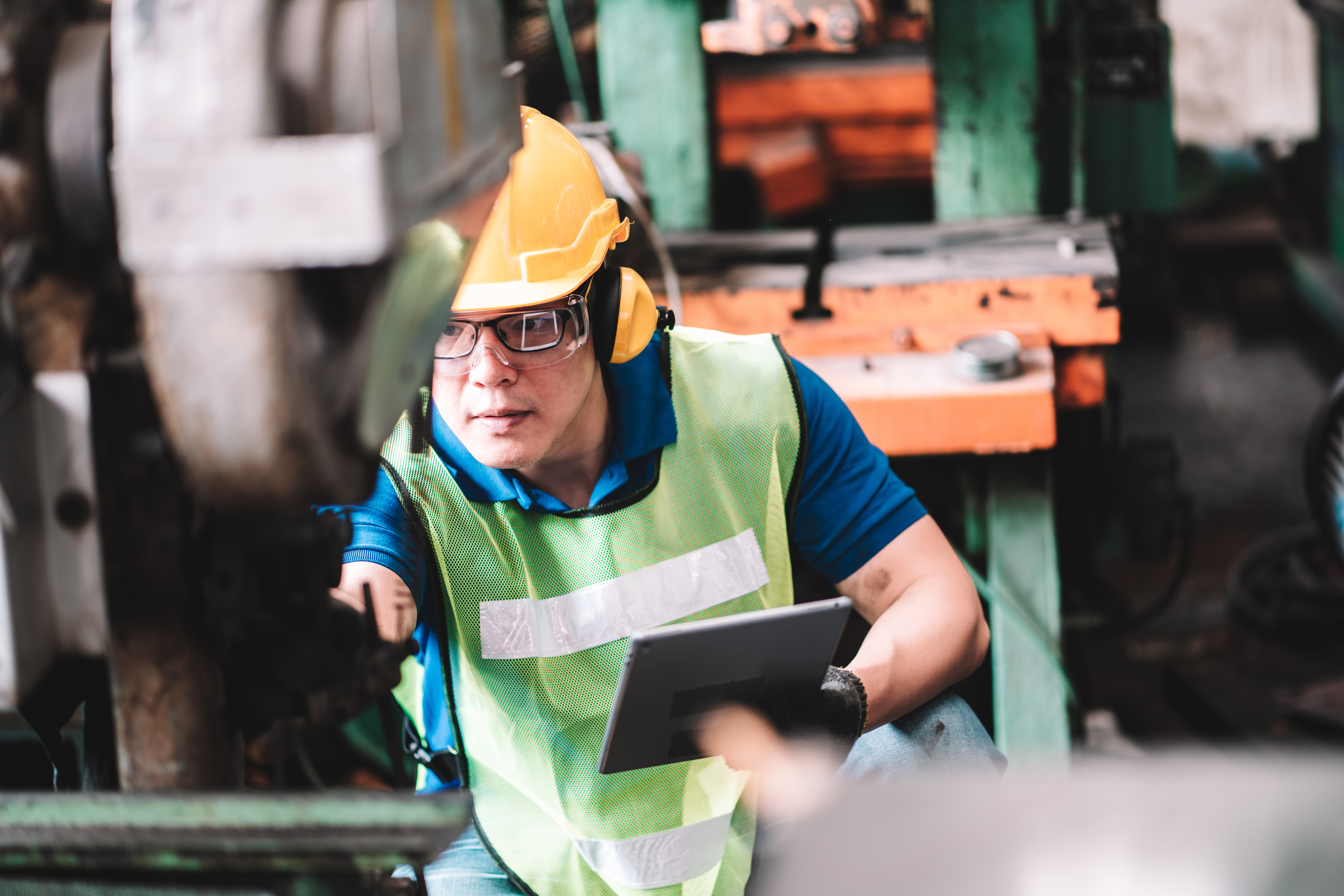 man with tablet working safely and inspecting equipment in factory