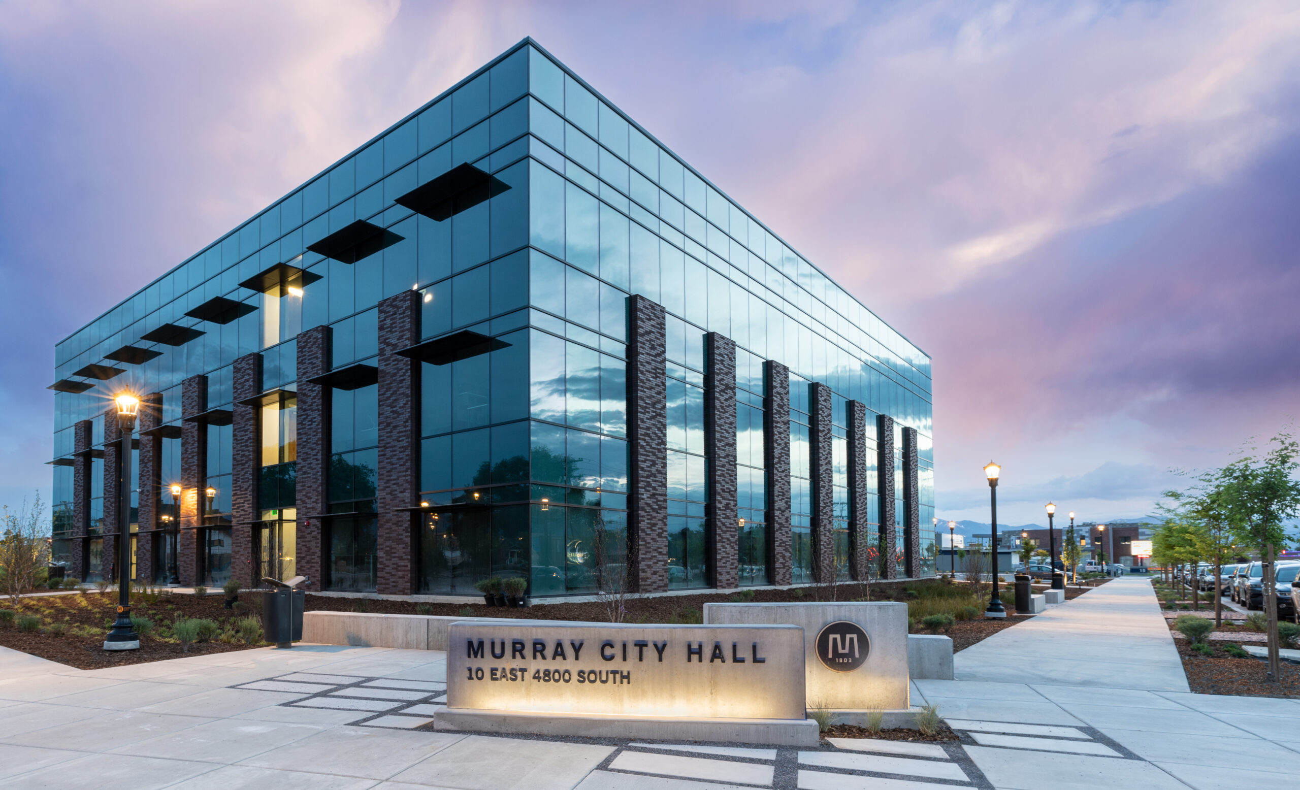 Front view of Murray City Hall full of windows and concrete signage at sunset